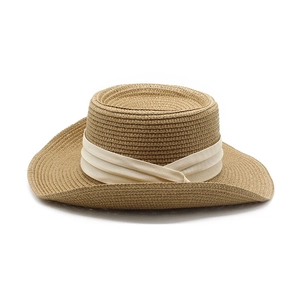 Detailed view of the woven texture and cream ribbon on a vintage straw sun hat