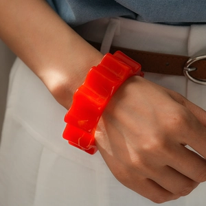 Dettaglio del bracciale rigido arancione acceso con bordi ondulati indossato