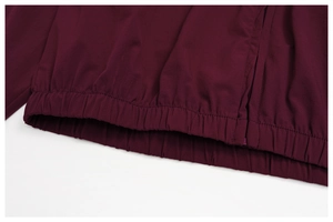 Detailed close-up of wine red jacket hem with elasticated waist and side zipper detail