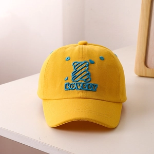 Close-up of yellow kids baseball cap with blue bear embroidery and Lovely text detail