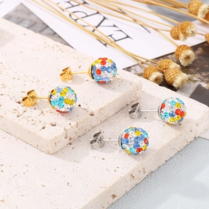 Detail shot of gold and silver sphere stud earrings with colorful rhinestones on stone