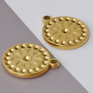 Macro shot of two golden stainless steel round flower pendants with detailed engravings