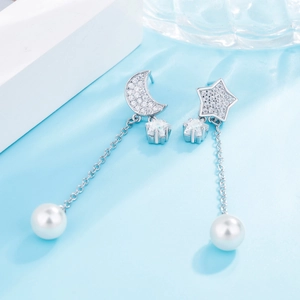Detailed close-up of asymmetric star and moon earrings with pearls and zircon stones