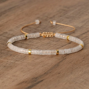 Verstelbare geweven armband met witte matte stenen kralen en gouden tussenstukken