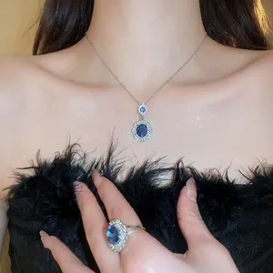 Elegant silver jewelry set featuring oval blue sapphire pendants with sparkling diamond accents