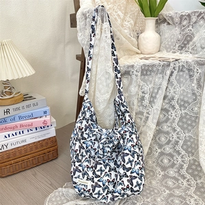 Detail of white canvas tote bag featuring blue butterfly prints and Sozakka woven label