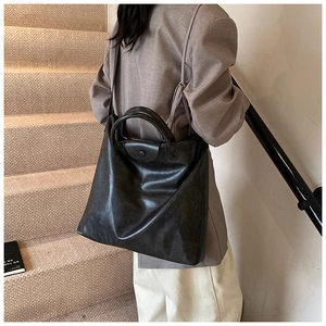 Detail van de zwarte PU-lederen tote bag met hoogglans afwerking en dubbele banden