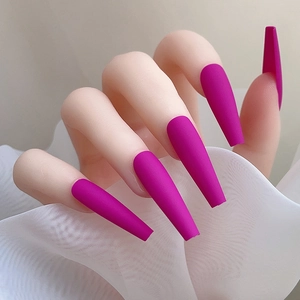 Vue macro de faux ongles longs magenta mat de forme coffin sur fond de mousseline blanche