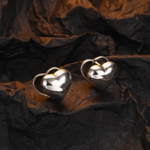 Polished double heart silver earrings with modern nested design on textured background