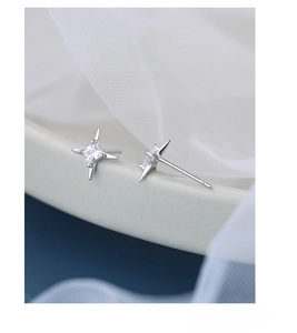 Macro view of S925 silver star stud earrings with square zircon on white ceramic