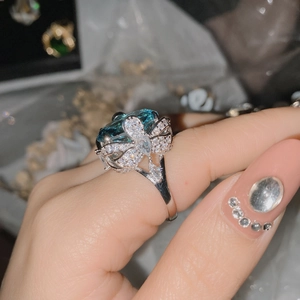 Macro detail of a butterfly ring featuring a large oval blue gemstone and 18k silver plating