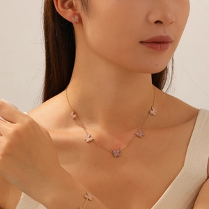 Détails des breloques papillon rose et violet sur une chaîne en acier plaqué or