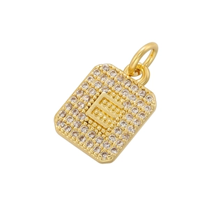 Macro shot of gold square pendant with cubic zirconia pavé and letter E charm