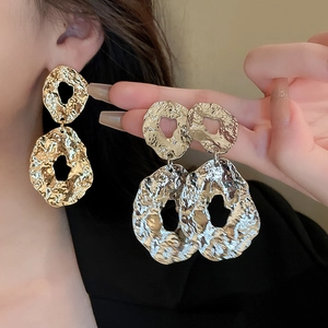 Detail of gold and silver geometric earrings with hammered metal texture for women