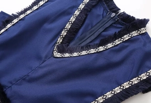 Détail du col en V avec franges et ruban rayé sur cette robe bleu foncé élégante