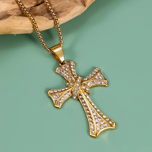 Close-up of a gold-plated punk cross pendant with white zircon stones on a ball chain
