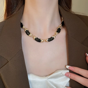 Gros plan d'un collier chaîne géométrique en émail noir et or sur un mannequin