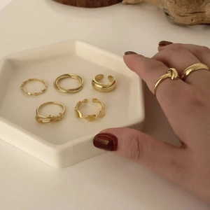 Detailed set of multiple minimalist gold-tone alloy rings on a white display tray
