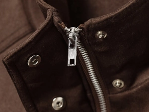 Details von dunkelbraunem Wildleder-Jackenkragen mit silbernem Reißverschluss und Druckknopf
