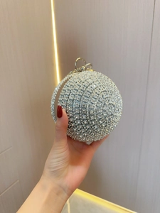 Close-up of a spherical silver evening bag featuring rhinestone pavé and a round metal handle