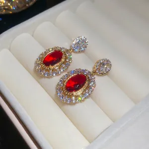 Elegant gold-plated oval stud earrings with red main stones and sparkling cubic zirconia