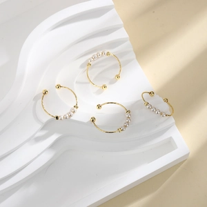 Detailed view of four elegant gold-finish rings set with white pearls on a wave texture base
