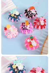 Macro detail of artificial miniature cupcakes with cream and fruit charms for bags