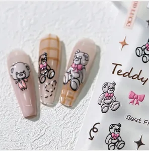 Detailed macro of 3D embossed teddy bear and pink bow nail art stickers on long nails