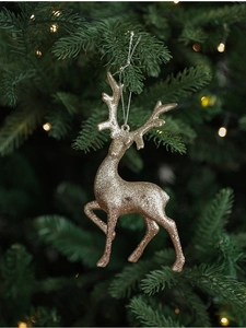 Detail of a champagne gold glitter reindeer ornament hanging on a Christmas tree branch
