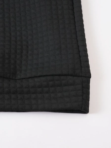 Close-up of black waffle knit fabric showing premium texture and ribbed hem detail