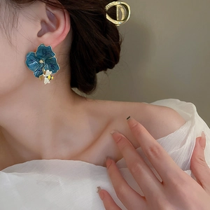 Elegant painted flower earrings with bee charms and gold metal base worn by model