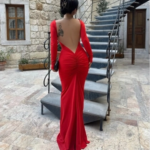 Back view of a red backless long-sleeve evening gown with ruched detail and floor-length hem