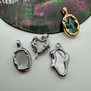 Macro shot of 18K gold and silver plated heart pendants with natural abalone shell inlays