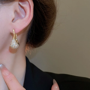 Détail de boucles d'oreilles dorées en U avec zircons ovales sur le lobe de l'oreille