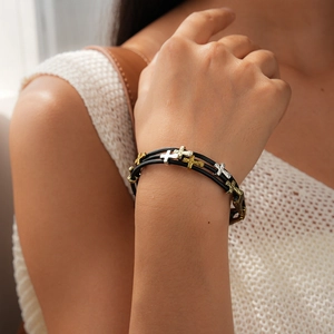 Détail de bracelet multicouche en cuir avec pendentifs croix martelés en or et argent
