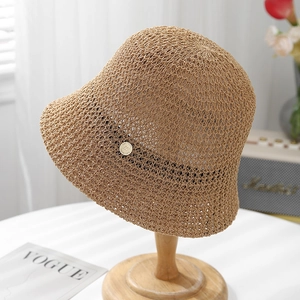 Beige hand-woven crochet bucket hat with black band and gold floral accent on a hat stand
