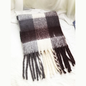 Detailed view of plaid checkered scarf with tassels in brown, grey, and white tones