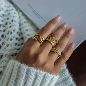 Close-up of a three-piece set of golden crown rings on model hands with cozy knit background