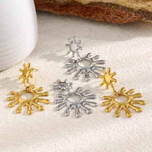 Gros plan de boucles d'oreilles étoile soleil or et argent sur surface en pierre blanche