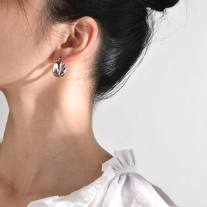 Close-up of a model wearing high-polish silver C-shaped chunky hoop earrings
