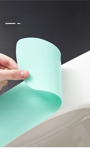 Macro detail of a flexible light green silicone toilet seat cover showing strong suction