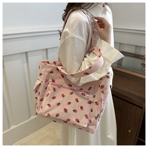 Detail of pink corduroy tote bag with red strawberry prints and functional front zipper pocket
