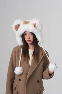 Close-up of winter faux fur bucket hat featuring animal ears and plush pom-pom drawstrings