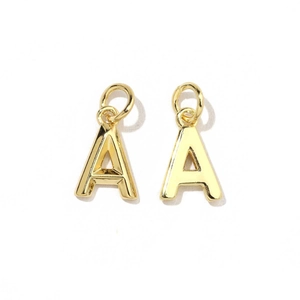 Macro shot of 18K gold plated letter Å charm with smooth finish and link ring