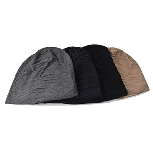 Detailed texture of four stacked knitted beanies in grey, black, navy and beige