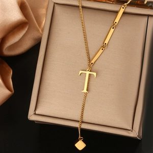 Detail van gouden titanium stalen ketting met letter T hanger en ruitvormige kwast