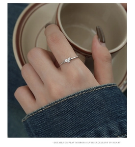 Close-up of minimalist S925 silver ring with a sparkling zircon heart on model's hand