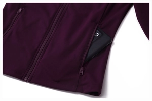 Detail of hidden zipper pocket on burgundy sports jacket holding a mobile phone