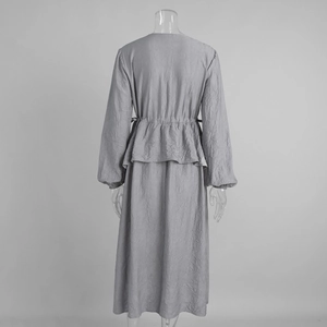 Détail de la robe grise plissée montrant le volant à la taille et le cordon au dos