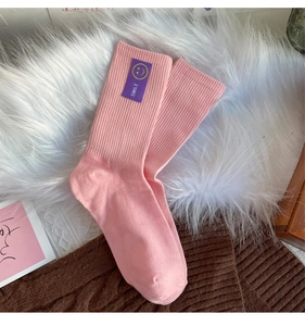 Vue détaillée de chaussettes en coton rose côtelé avec un écusson sourire violet